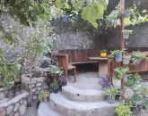 نیمکت های چوبی و محوطه سنگ فرش شده و باغچه ی سرسبز محوطه ویلا در نیشابور