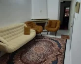 اتاق پذیرایی فرش شده و مبلمان خردلی و سفید به همراه شومینه آیفون معمولی آپارتمان در مشهد 4856497