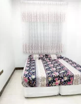 تخت خواب با روتختی رنگی و پرده سفید صورتی اتاق خواب آپارتمان در تربت جام